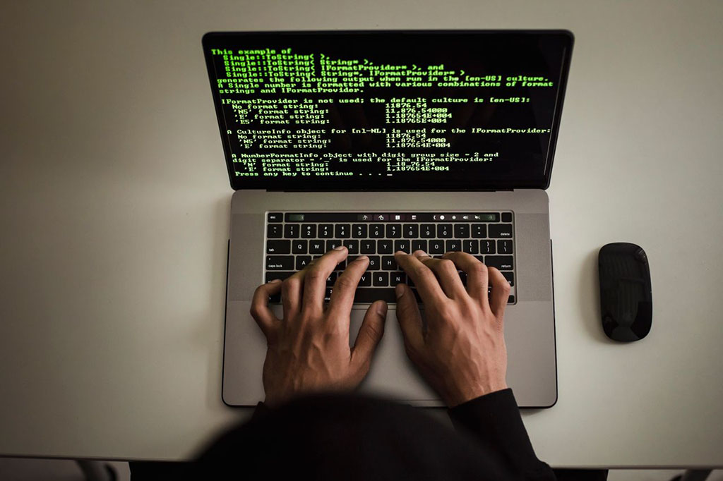Faceless Developer Working on Software Code on Laptop